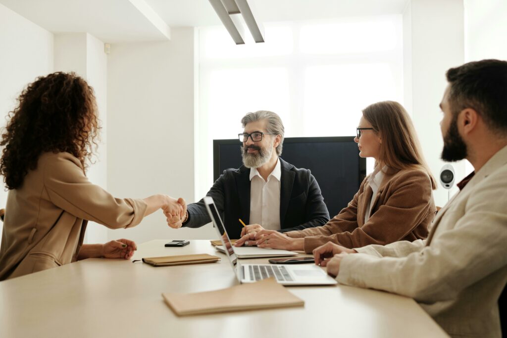 A woman sits with a group of HR professionals at a table after passing her micro credential course 