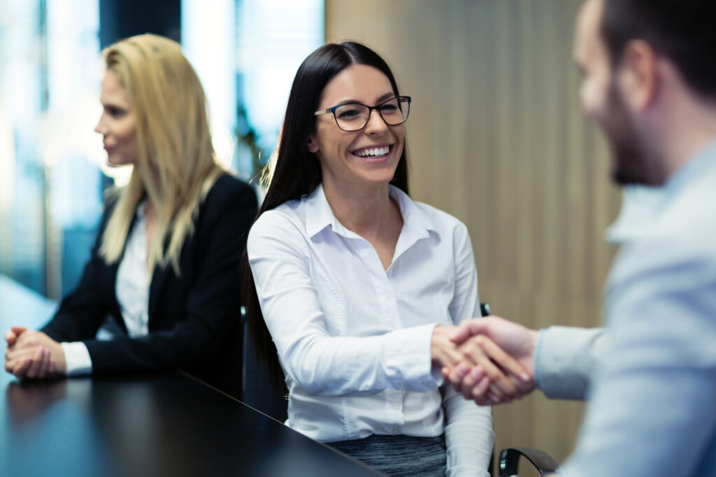  A happy female HR professional shaking hands with a male colleague 