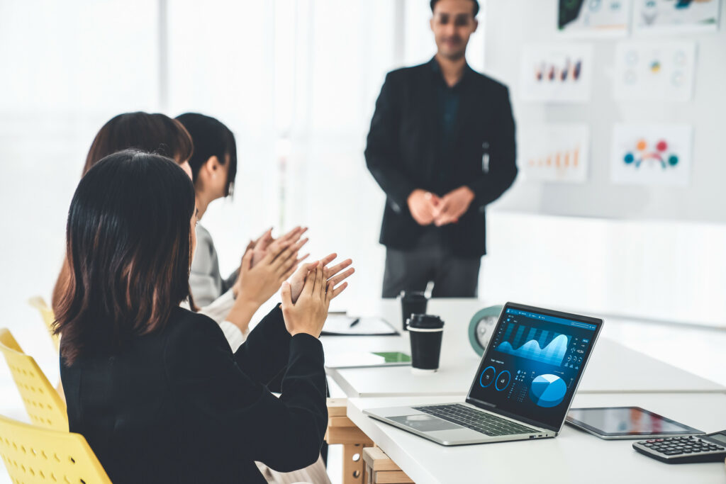 A group of employees applauding their HR representative for their business strategy in a modern conference room