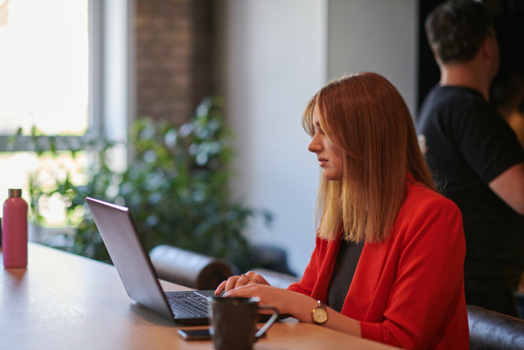 A woman learning how to use AI in HR on her laptop with a coffee mug