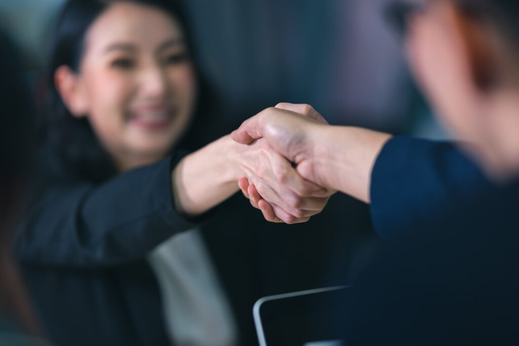 A woman and employer shaking hands after a successful HR job interview