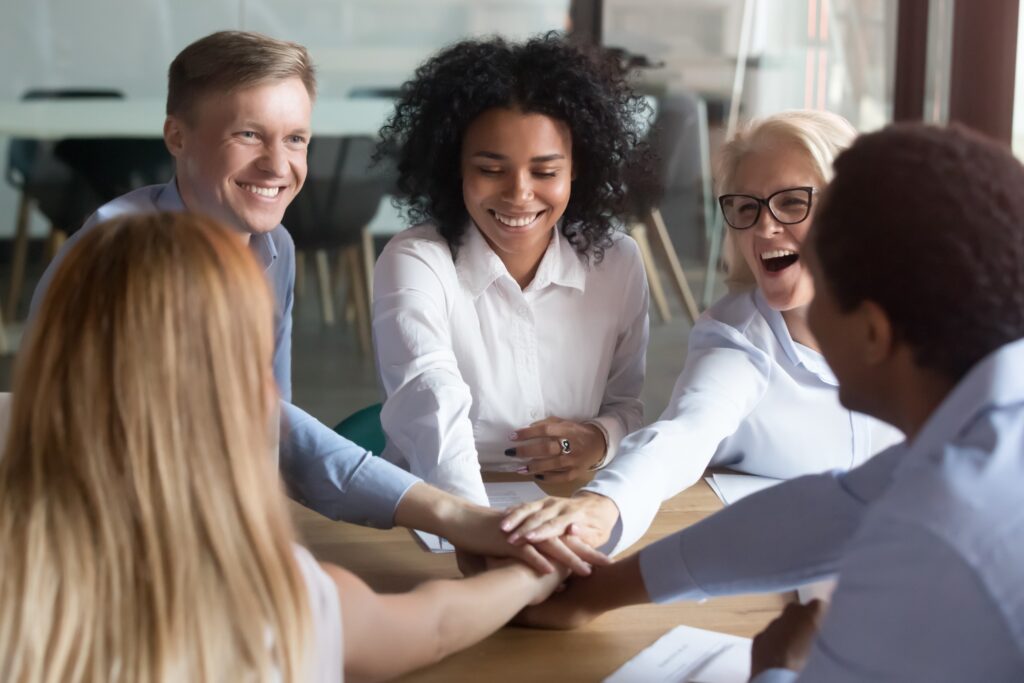 A group of diverse business employees stacking hands in a pile as part of their company culture type