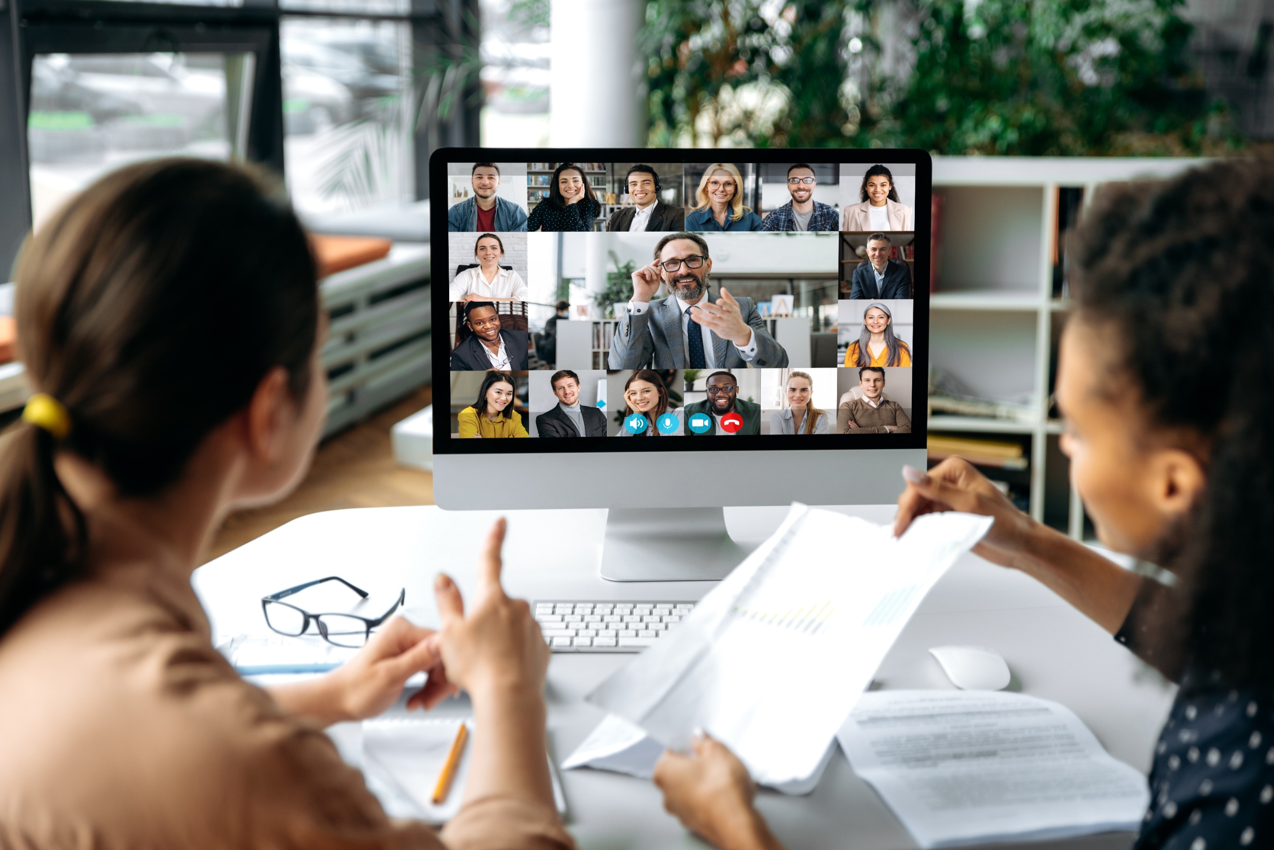 Two Female Employees On A Hybrid Virtual Work Call On The Computer With Remote Employees