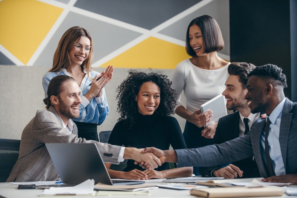 HR professionals shaking hands after a hybrid team meeting